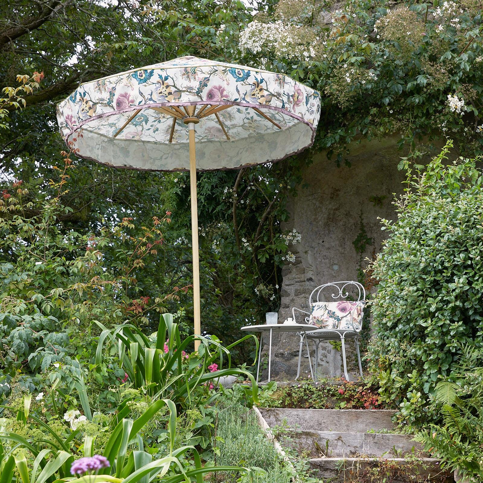 a white umbrella and chair in a garden