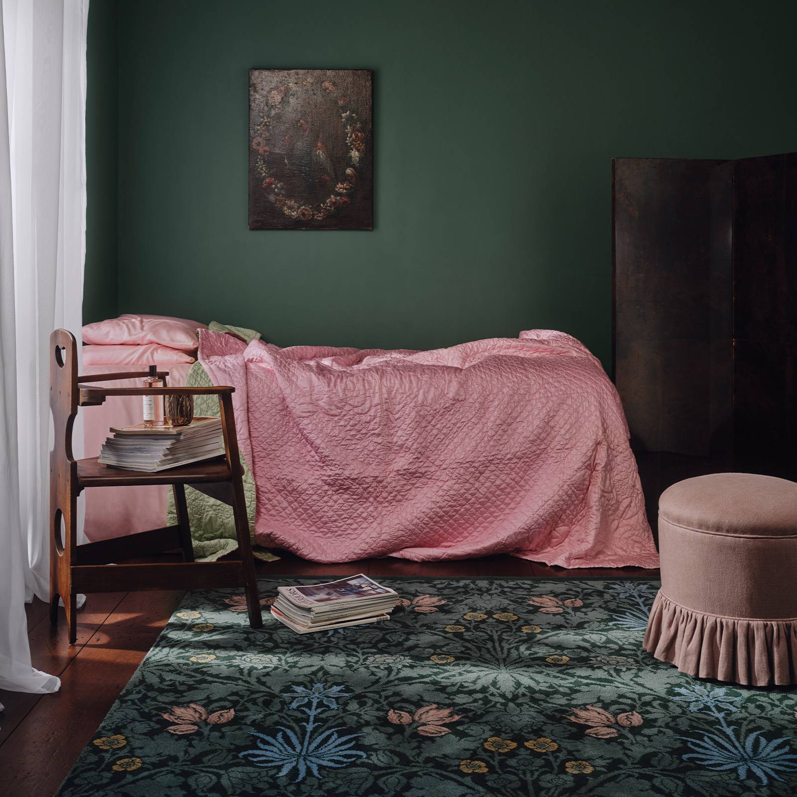 a pink bed with a pink blanket and a green rug
