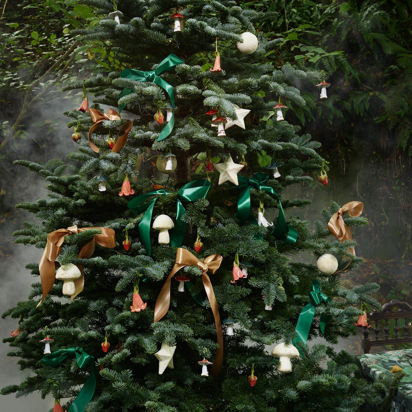 a christmas tree with ornaments and a bed in the background